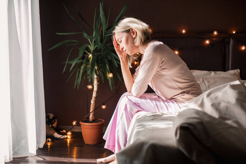 TIred, exhausted woman sitting on her bed