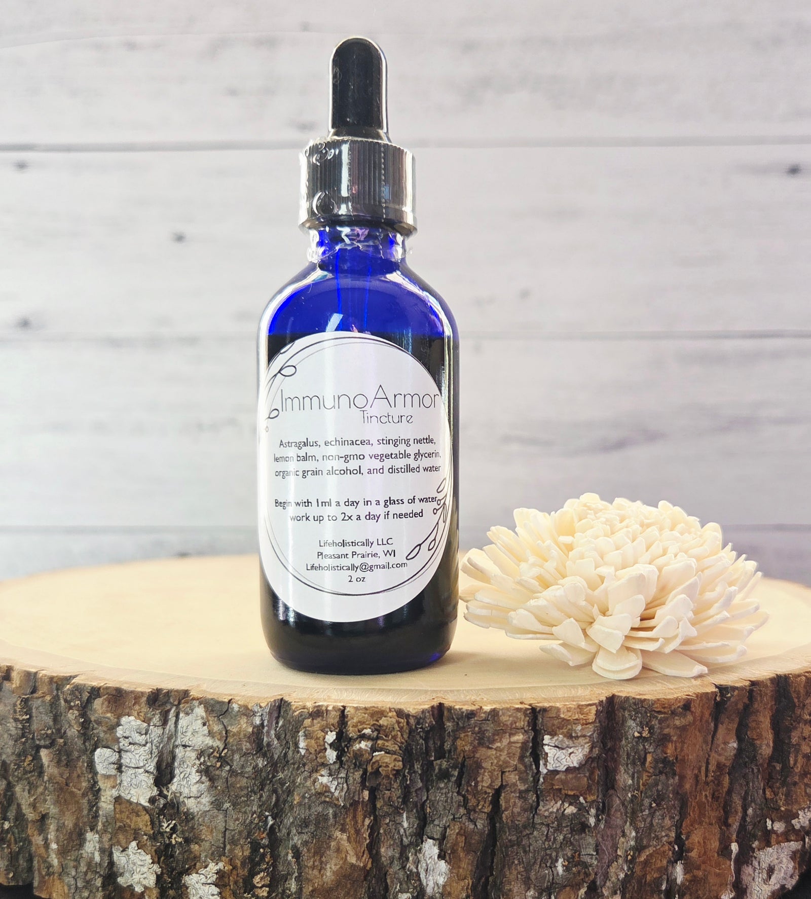 Bottle of ImmunoArmor tincture displayed with astragalus, echinacea, nettle, and lemon balm.