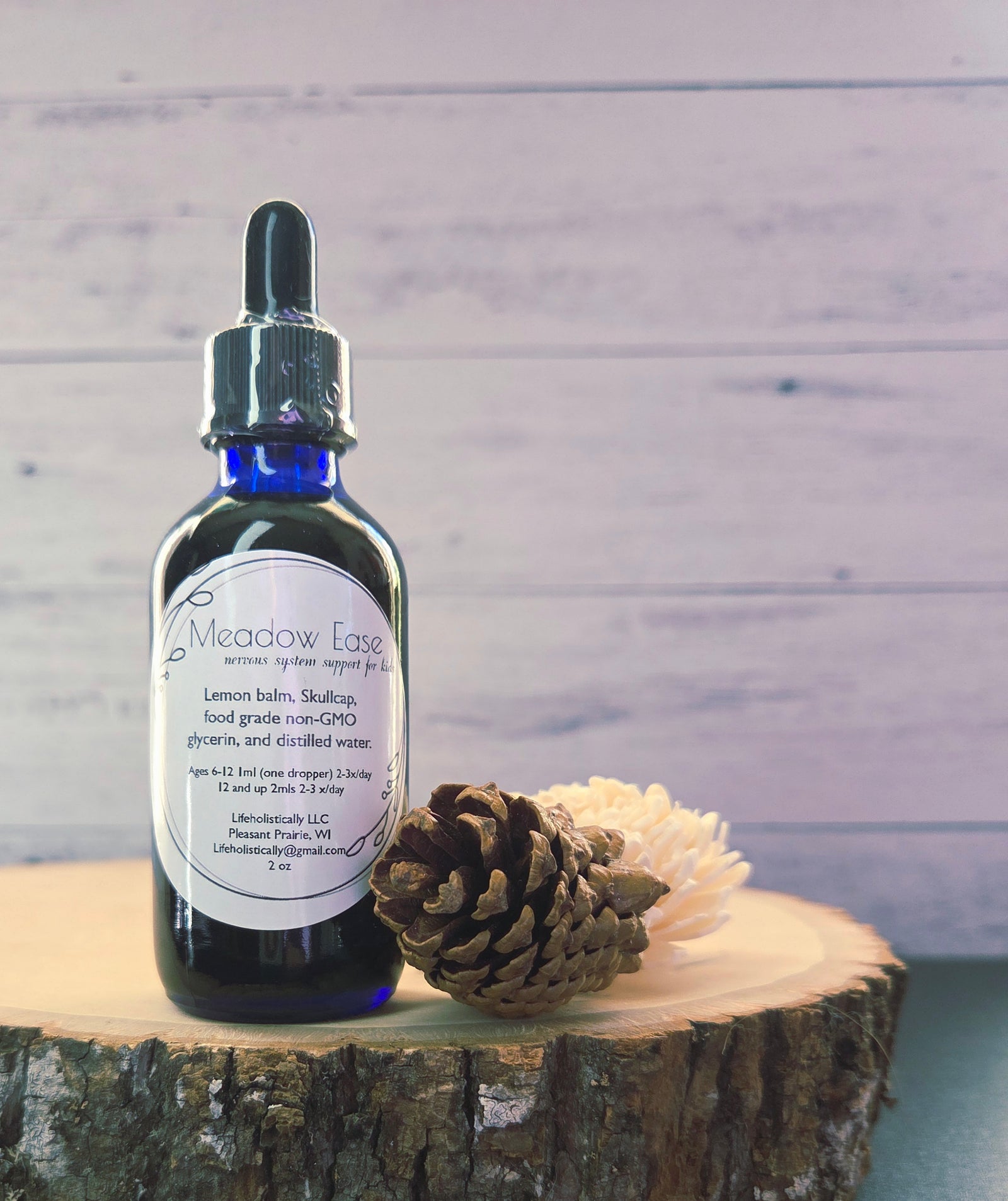 Meadow Ease herbal glycerite bottle displayed with fresh lemon balm and skullcap.