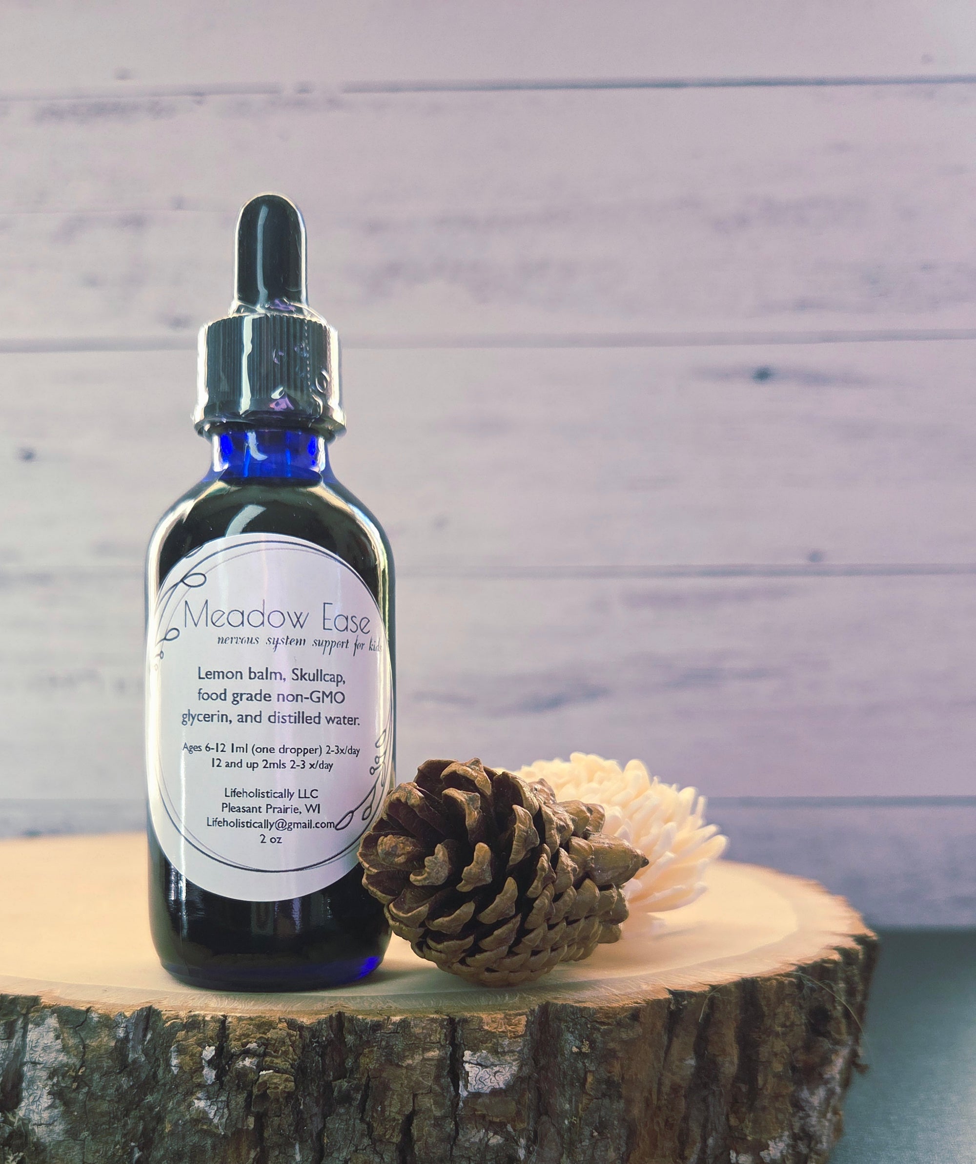 Meadow Ease herbal glycerite bottle displayed with fresh lemon balm and skullcap.